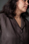 Close-up of a person wearing a brown shirt against a neutral background