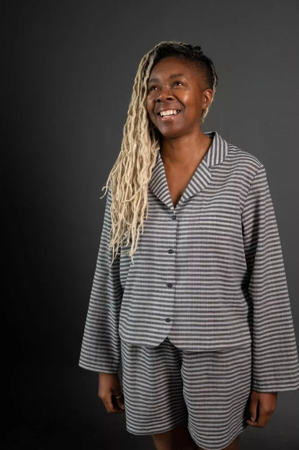 Person wearing a gray and white striped pajama set against a black background