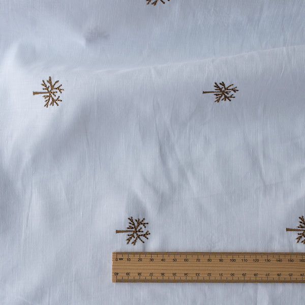 White fabric with brown snowflake patterns and a wooden ruler for scale.
